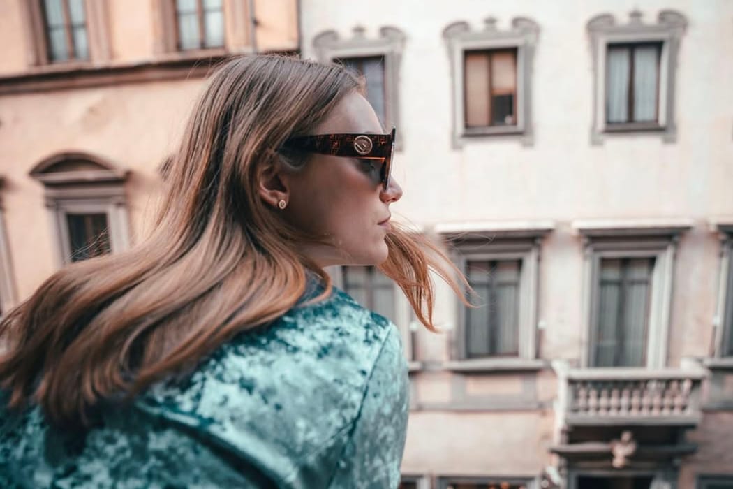 Girl wearing sunglasses looking out from the balcony